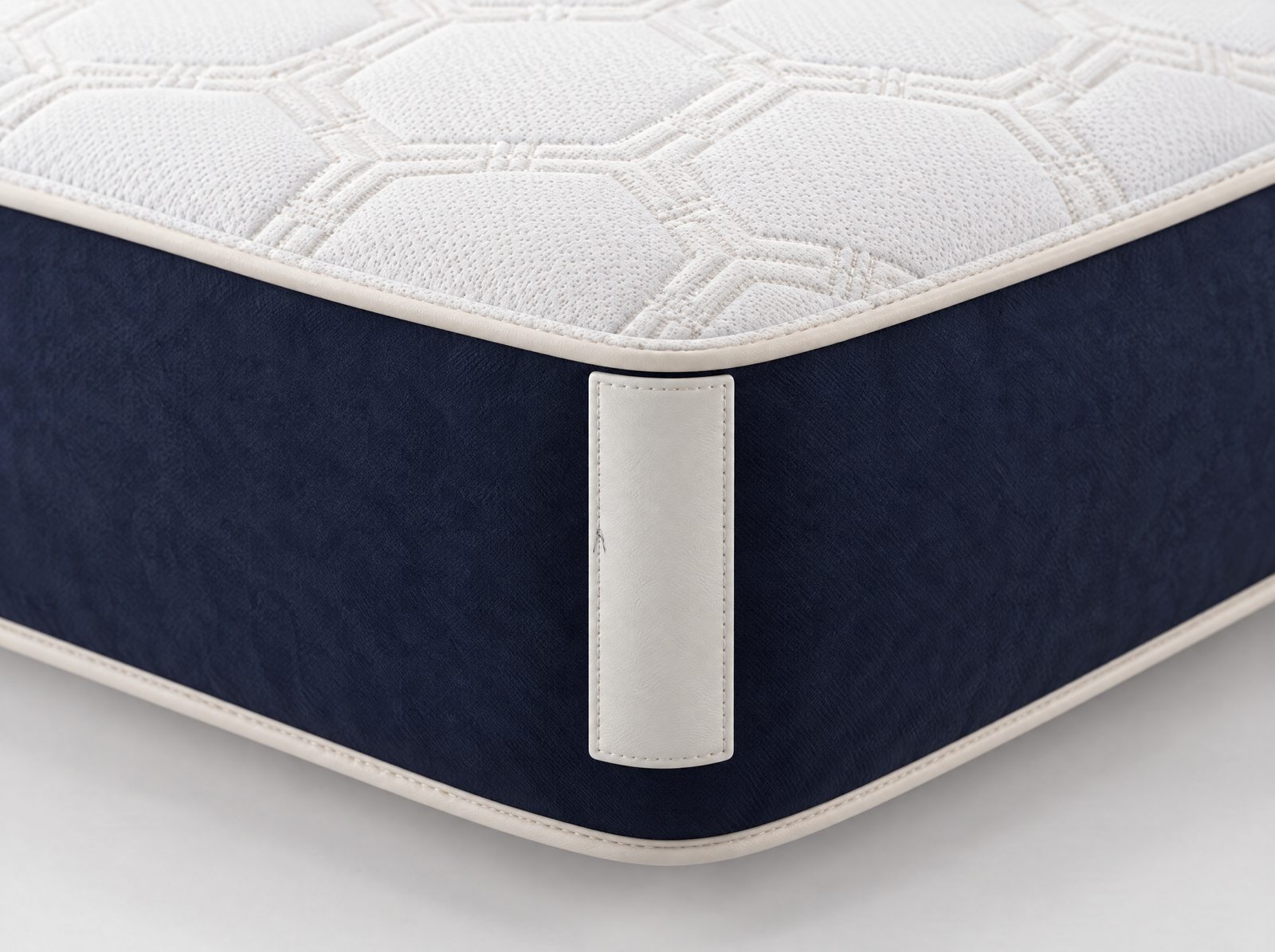 Etiqueta de couro branco com o monograma em azul, em relevo, na quina do colchão